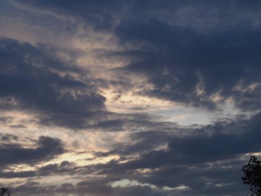 Batan güneşin parlaklığında gri ve mavi bulutlarla trajik bir gökyüzü.