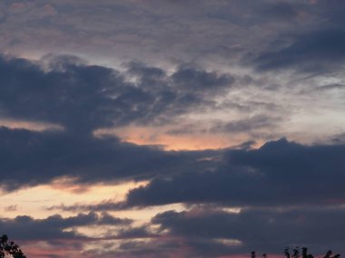 Batan güneşin parlaklığında gri ve mavi bulutlarla trajik bir gökyüzü.