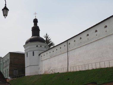 Beyazlatılmış kadim manastır duvarı üzerinde asfalt bir yol ile toprak bir duvar