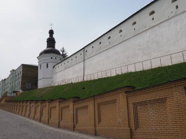 Beyazlatılmış kadim manastır duvarı üzerinde asfalt bir yol ile toprak bir duvar