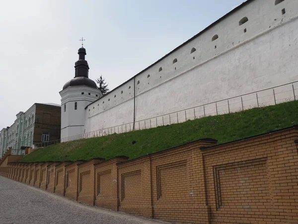 Beyazlatılmış kadim manastır duvarı üzerinde asfalt bir yol ile toprak bir duvar