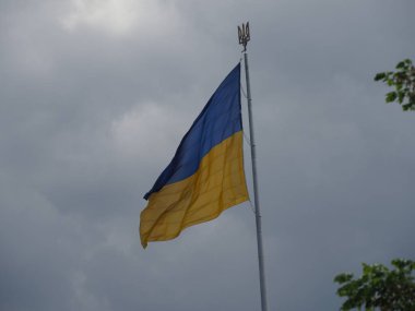 Bayrak direğindeki büyük Ukrayna bayrağı. Üzerinde devlet amblemi var. Üç dişli bir mızrak.