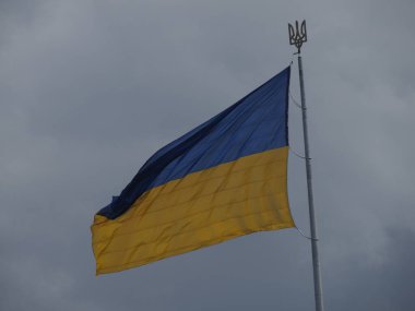 Bayrak direğindeki büyük Ukrayna bayrağı. Üzerinde devlet amblemi var. Üç dişli bir mızrak.