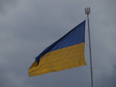 Bayrak direğindeki büyük Ukrayna bayrağı. Üzerinde devlet amblemi var. Üç dişli bir mızrak.