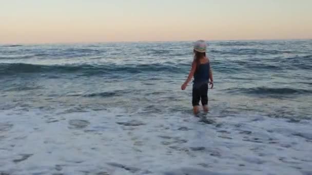 Одинокая Девушка Вязаной Шляпе Синих Штанах Пустынном Морском Пляже Пенными — стоковое видео