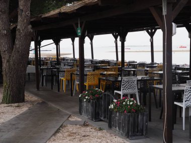 Plastik mobilyalı insanların olmadığı açık deniz kıyısında bir kafe.