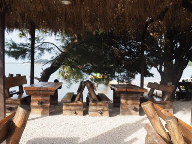 Sahilde, ahşap masaları ve koltukları olan insanların olmadığı bir kafenin içinde.