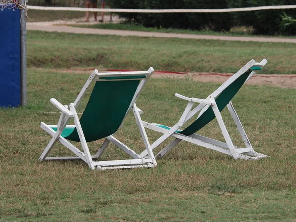 two folding chairs on a lawn of green grass without people