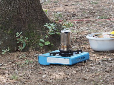 Geyser Coffee maker made of shiny steel on a portable gas stove in the campsite