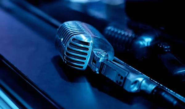 Mikrofon Pięknym Niebieskim Podświetleniu Leży Obok Szkła Odbija Się Szkle — Zdjęcie stockowe