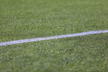 Yeşil doğal çimenlikli bir futbol sahasında beyaz işaret şeridi