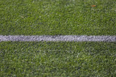 Yeşil doğal çimenlikli bir futbol sahasında beyaz işaret şeridi