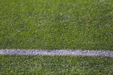 Yeşil çimenli bir futbol sahasında beyaz işaret şeridi