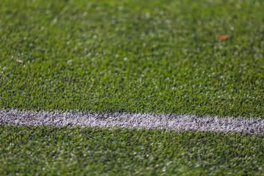 Yeşil çimenli bir futbol sahasında beyaz işaret şeridi