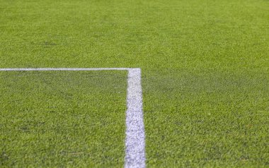 Yeşil çimenli bir futbol sahasında beyaz işaret şeridi