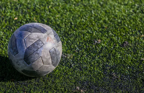 A soccer ball lies on a natural soccer field covered with green grass