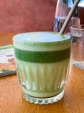 Bardakta vejetaryen hindistan cevizi sütüyle latte, bir restorandaki ahşap masada.