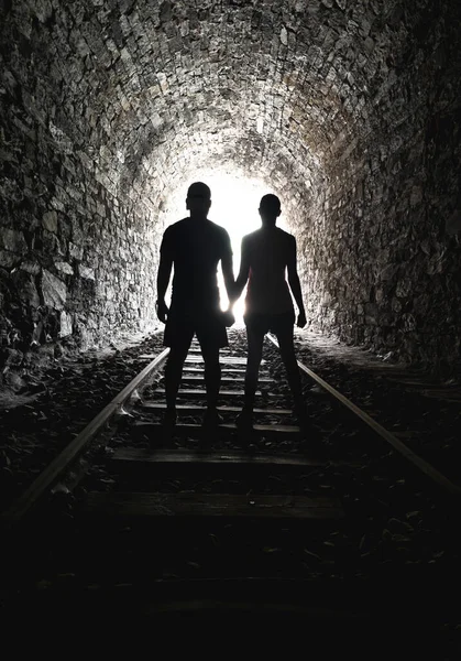 Silhouette couple holding hands end tunnel