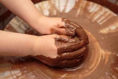 Çocuk çömlekçinin tekerindeki çömlek kalıbından şekilleniyor.. 