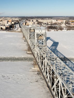 Arkhangelsk, Rusya - 11 Mart 2021 Kışın demir köprü ve donmuş nehir boyunca bir şehir manzarası.