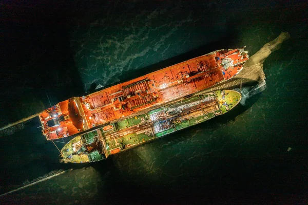 Two tankers at night, stand nearby in young ice. Shooting from air.