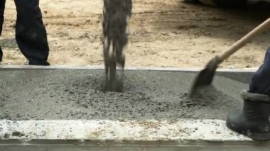 İşçiler evin formalitelerine beton döküyorlar. İşçiler ev işlerinde betonu temizler ve düzleştirirler..