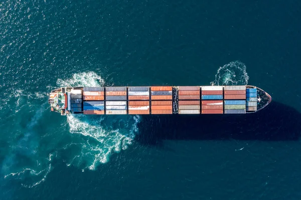 Deniz konteynırı gemisi denizde hareket ediyor. Çivinin çıkardığı köpüğün etrafında. Yukarıdan geminin görüntüsü.