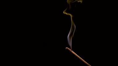 Aroma çubuğu yanar ve sigara içer. Renkli duman yavaş çekimde ve yakın çekimde çekilir..