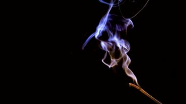 An incense stick burns and smokes.