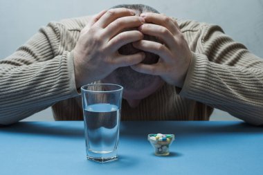 Adam yüzünü gizliyor, tıbbi hazırlıklar masanın önünde..