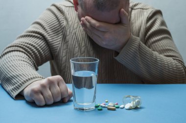 Adam yüzünü gizliyor, tıbbi hazırlıklar masanın önünde..