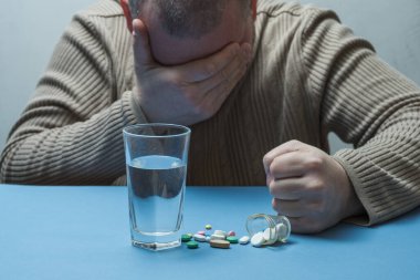 Adam yumruklarını sıkıyor, tıbbi hazırlıklar yapıyor ve önünde bir bardak su duruyor..