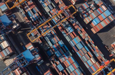 Deniz konteynırları ve çalışan iskele vinçleri..