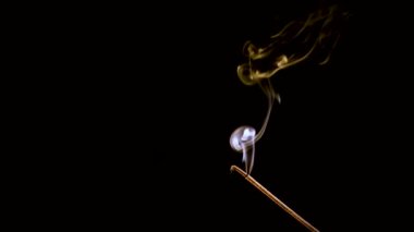 Aroma çubuğu yanar ve sigara içer. Renkli duman yavaş çekimde ve yakın çekimde çekilir..