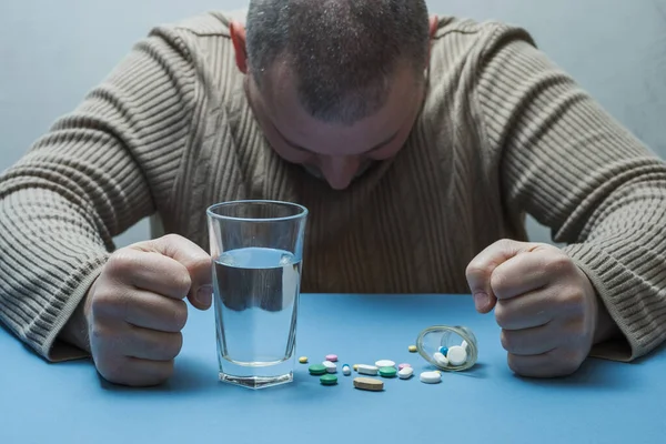 Adam yumruklarını sıkıyor, tıbbi hazırlıklar yapıyor ve önünde bir bardak su duruyor..