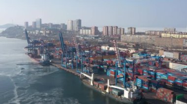 Vladivostok, Rusya - 27 Ocak 2022: Liman konteynır terminali ve şehrin üst görüntüsü. Winter, bir konteyner gemisi rıhtıma yükleniyor..