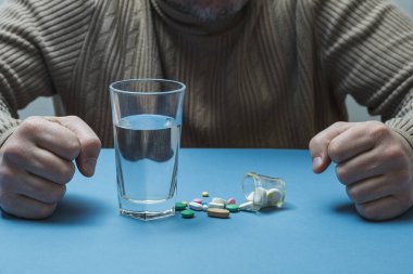 Adam yumruklarını sıkıyor, tıbbi hazırlıklar yapıyor ve önünde bir bardak su duruyor..