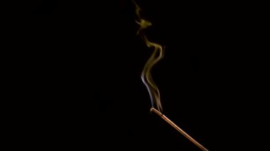 Aroma çubuğu yanar ve sigara içer. Renkli duman yavaş çekimde ve yakın çekimde çekilir..