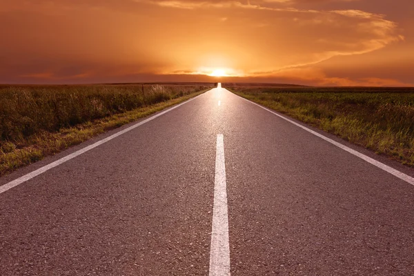 夕日に向かって空の道路上で運転 — ストック写真