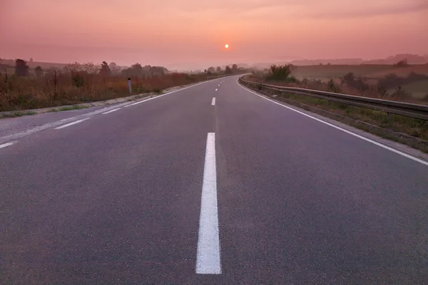 Condução em estrada vazia ao nascer do sol — Fotografia de Stock