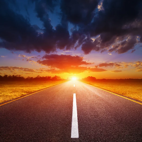 Driving on an empty road towards the setting sun — Stock Photo, Image