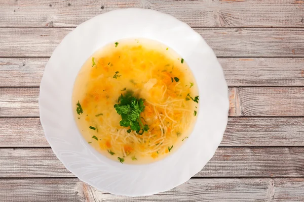 Yukarıdan bir tabak çorba ve eski bir ahşap masa ile görüntüleyin