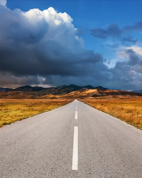 Conduciendo por un camino de asfalto vacío a las montañas —  Fotos de Stock