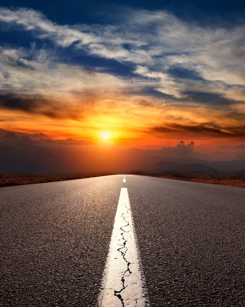 Rijden op een snelweg lege asfalt naar de bergen bij zonsondergang — Stockfoto