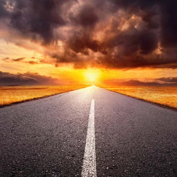 Driving on an empty road towards the setting sun — Stock Photo, Image