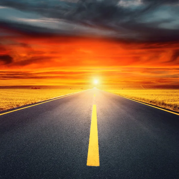 Водіння порожньою асфальтовою дорогою до заходу сонця — стокове фото