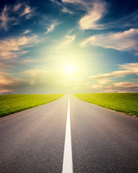 Rijden op asfaltweg naar de ondergaande zon — Stockfoto