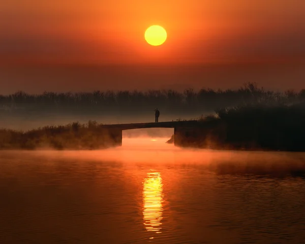 Eenzame man op de brug bij zonsondergang — Stockfoto