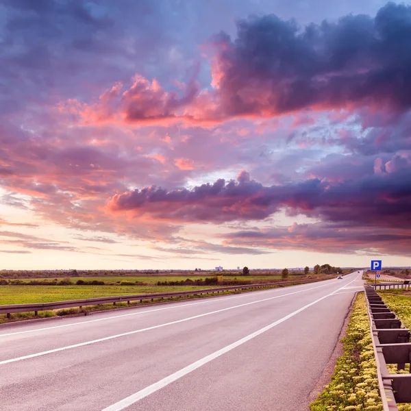 Condução em uma estrada de asfalto aberto ao pôr do sol — Fotografia de Stock