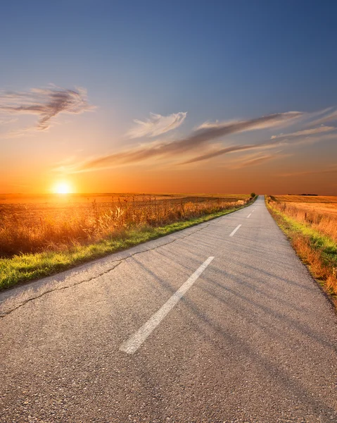 Fahren auf eine leere Aspalt-Straße bei Sonnenuntergang — Stock fotografie